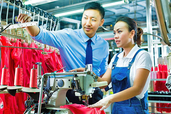 Business man training woman in sewing factory