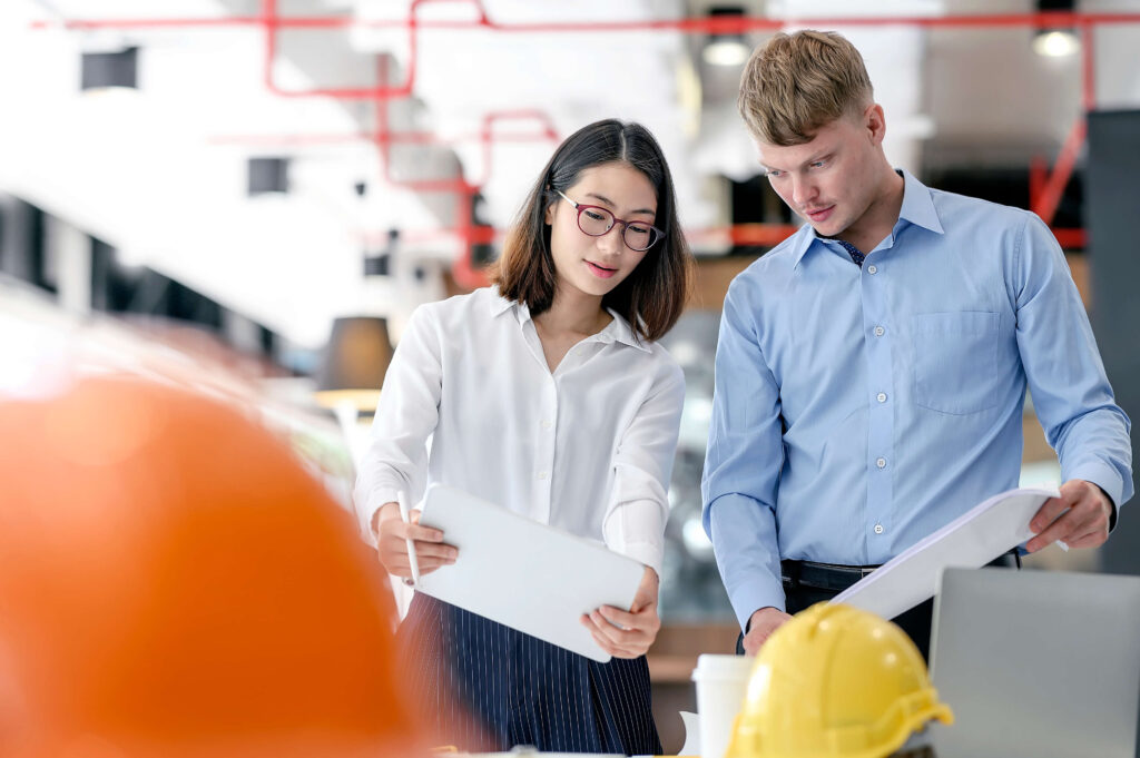 Man and woman discussing paperwork in factory